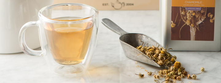 Cup of organic chamomile tea and whole leaf tea on a table.