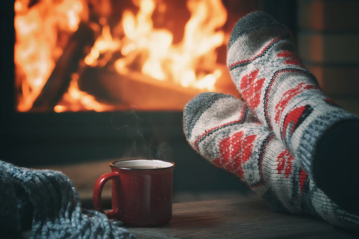 person relaxing by a warm fire enjoying a cup of tea