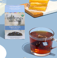 Two Leaves and a Bud Organic Earl Grey tea packaging with a cup of tea and pastries on a blue background