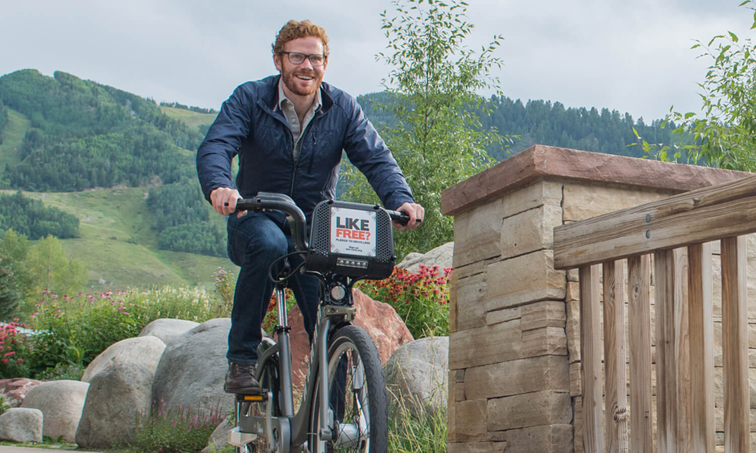 Man riding a bike with LIKE SPIN branding in a scenic outdoor setting.