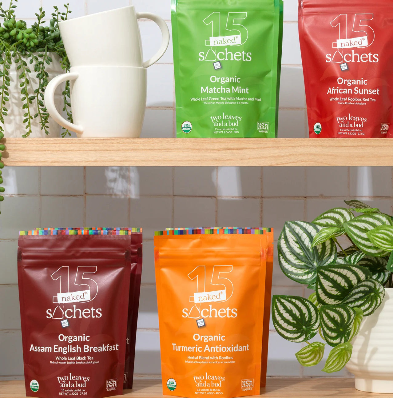 Naked Sachets tea packages on a wooden shelf with cups and plants.