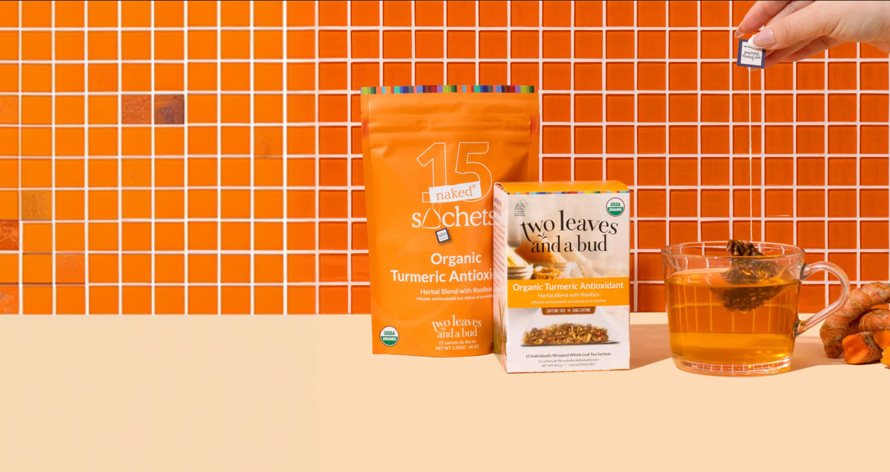 Tea packaging and a cup of tea on a table with an orange tiled wall background