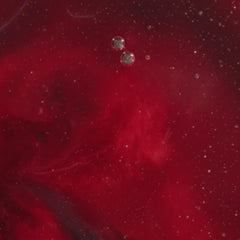 Close-up of a red substance with bubbles and particles