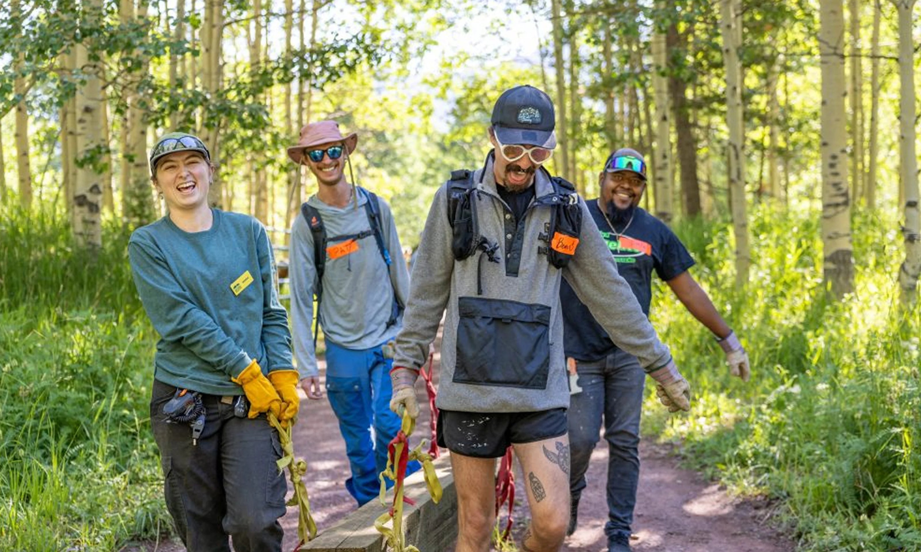 Four people hiking on a trail in a forested area