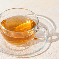 Clear glass mug filled with amber liquid on a light surface